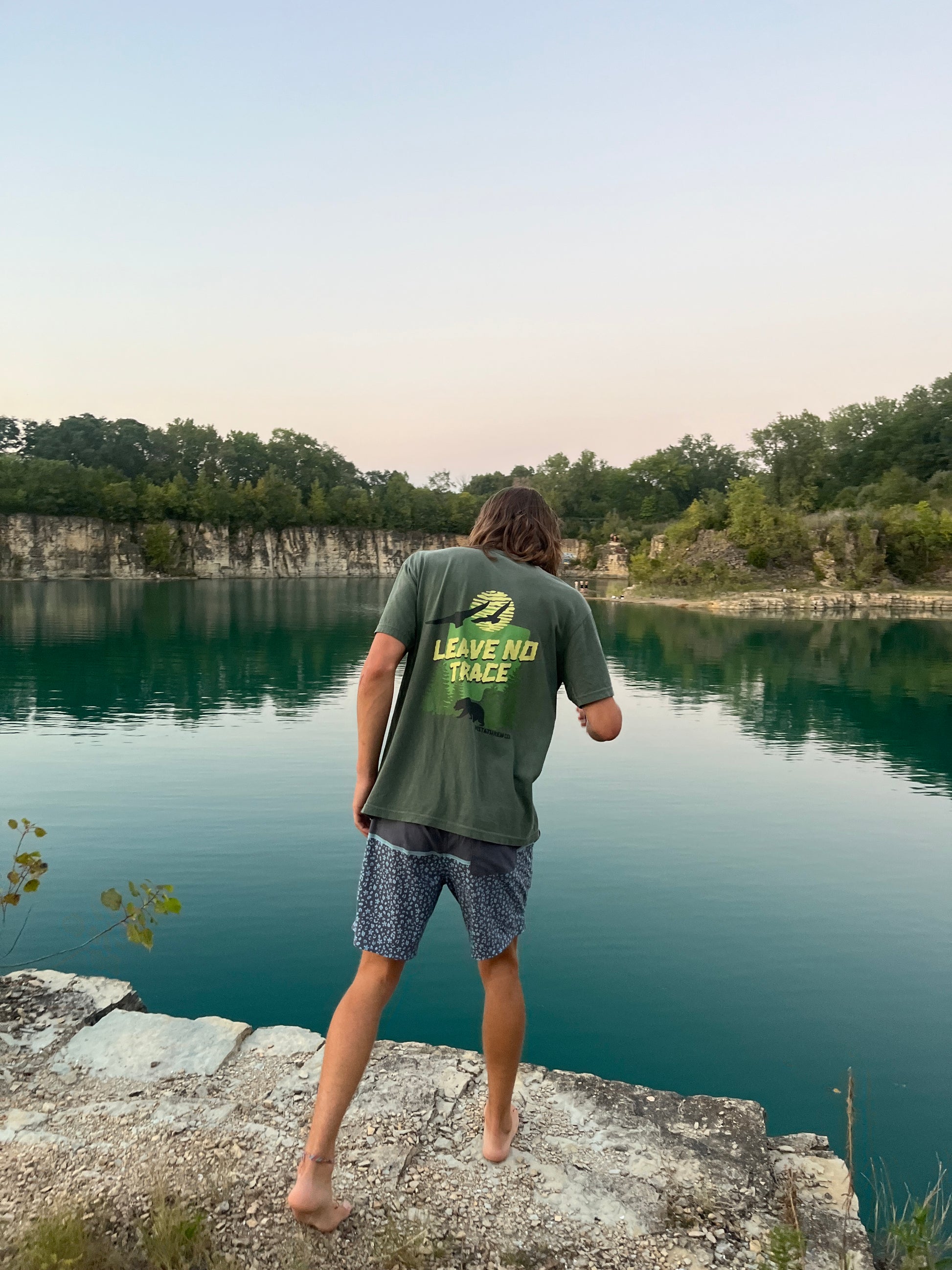 Leave No Trace Vistathread T-shirt model looking over cliff into water. 