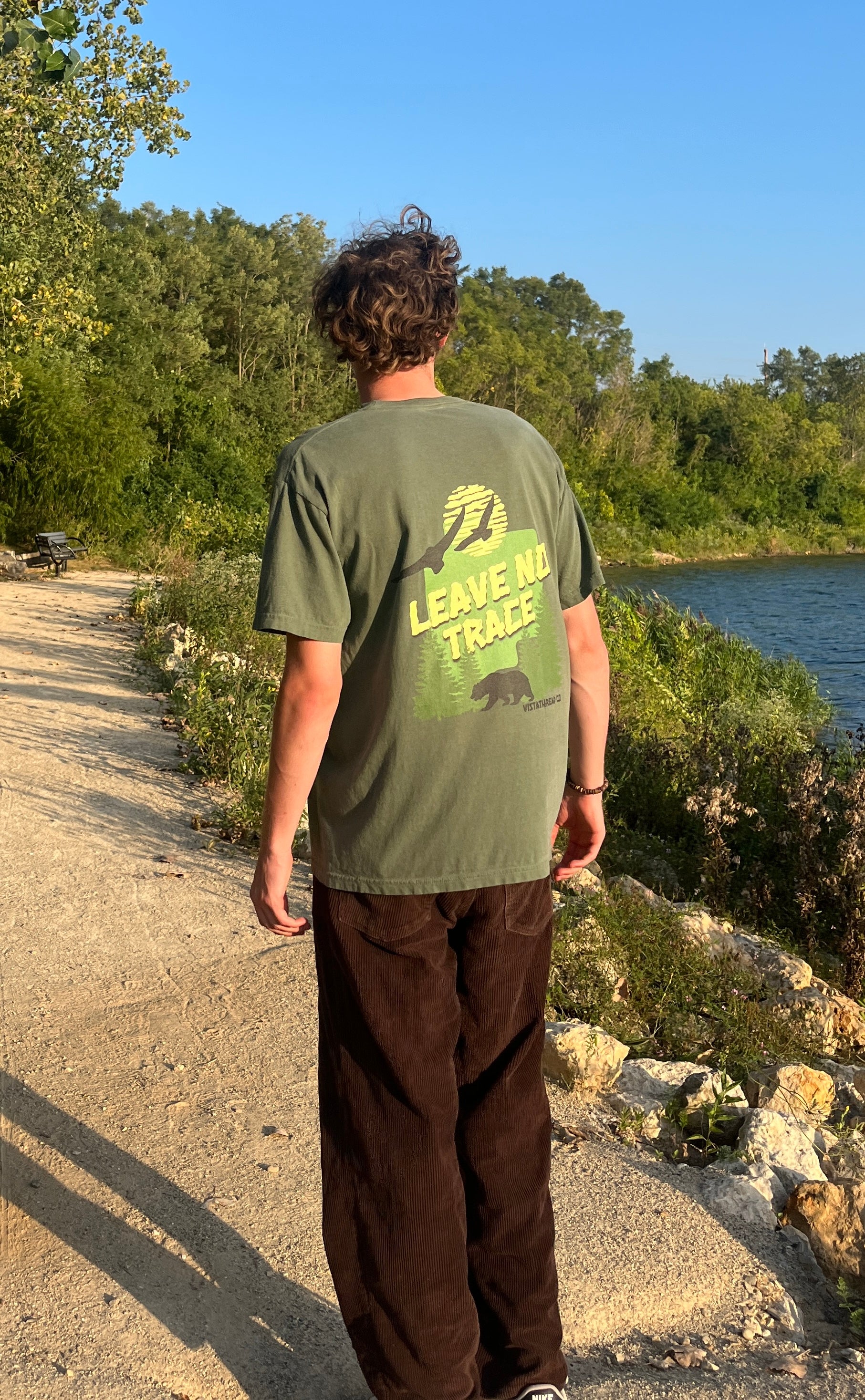 Vistathread Leave No Trace Forest T-shirt model wearing corduroy briwn pants looking away.